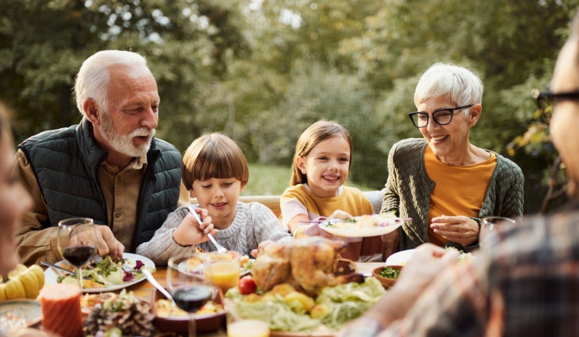 Happy extended family talking during a meal in nature.