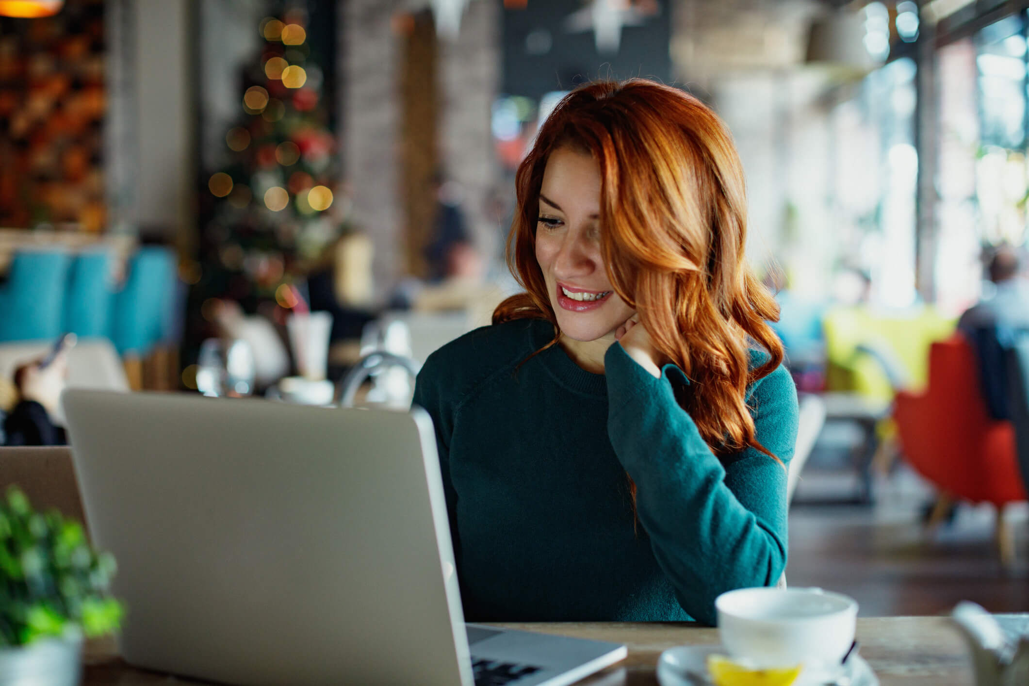 Woman with a green sweater looking at laptop during the holiday season