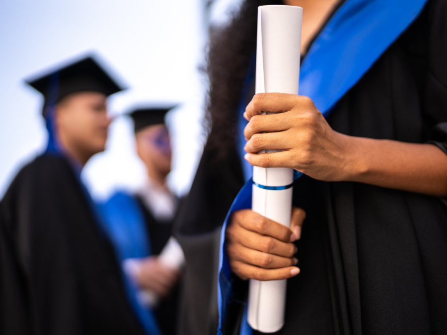 Close-up of a young woman holding a diploma on graduation